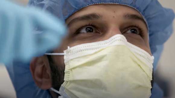 Closeup view of a gastroenterology fellow's face as he looks up at the monitor during an endoscopy.