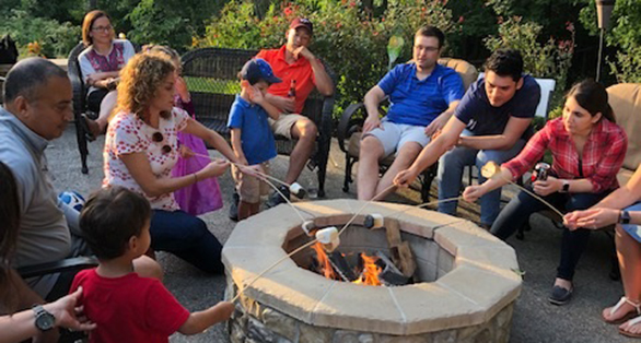 Group of students sitting around a fire pit and toasting marshmallows