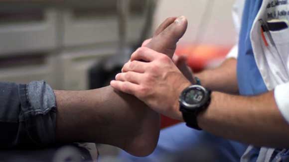 A foot and ankle surgical resident examines the foot of a black male patient.