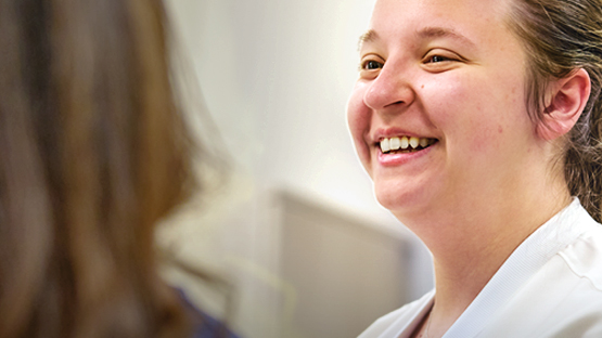 A nurse laughing while talking to fellow nurse.