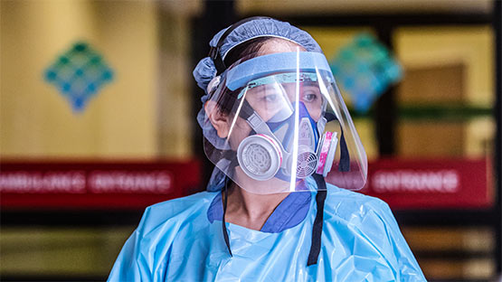 A medical professional in full PPE waiting for incoming ambulance.