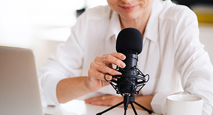 Female physician in white collard shirt giving a podcast interview in front of a microphone