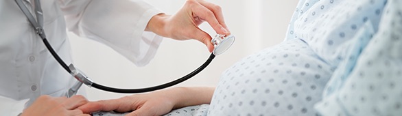 doctor using stethoscope on pregnant woman’s belly