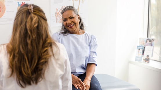 AHN patient in exam room smiling while talking to her doctor