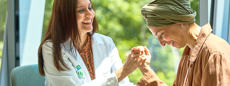Cancer patient smiling while holding hands with a member of her AHN Cancer Navigation team 