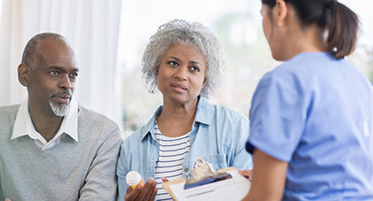 A nurse talking with two elderly patients